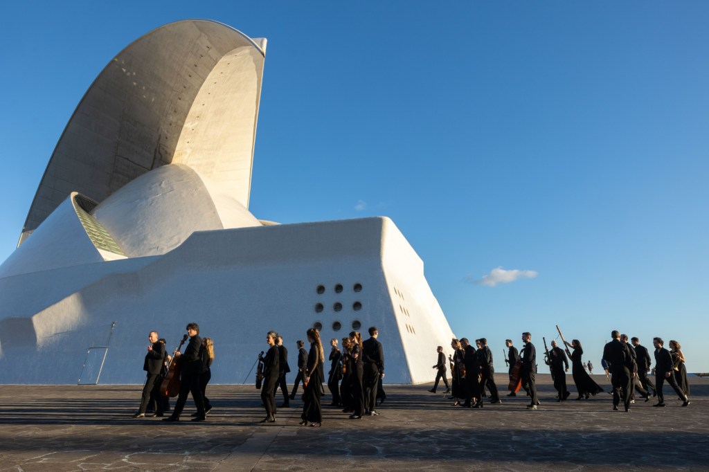 Members of Concerto München walking with their instruments in front of the Auditorio de Tenerife